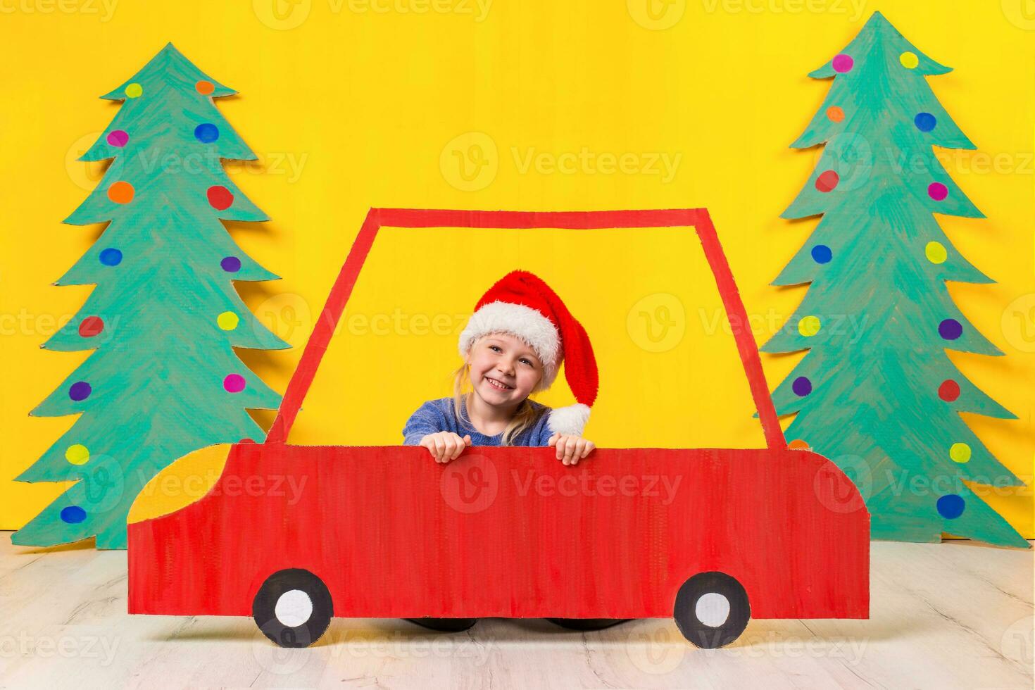 Kind mit Weihnachten Hut Fahren ein Auto gemacht von Karton. Weihnachten Konzept. Neu Jahre Feiertage. foto