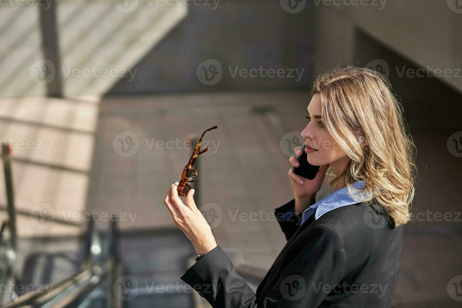 Porträt von korporativ Frau Stehen auf Rolltreppe, Herstellung ein Telefon Forderung, mit Smartphone, Gehen im Stadt foto