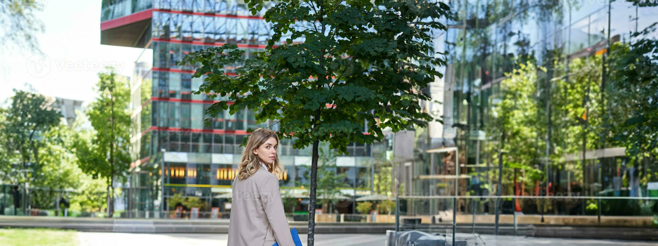 Porträt von Geschäftsfrau Gehen auf Straße von ein leeren Stadt Center, halten Mappe mit Arbeit Unterlagen foto