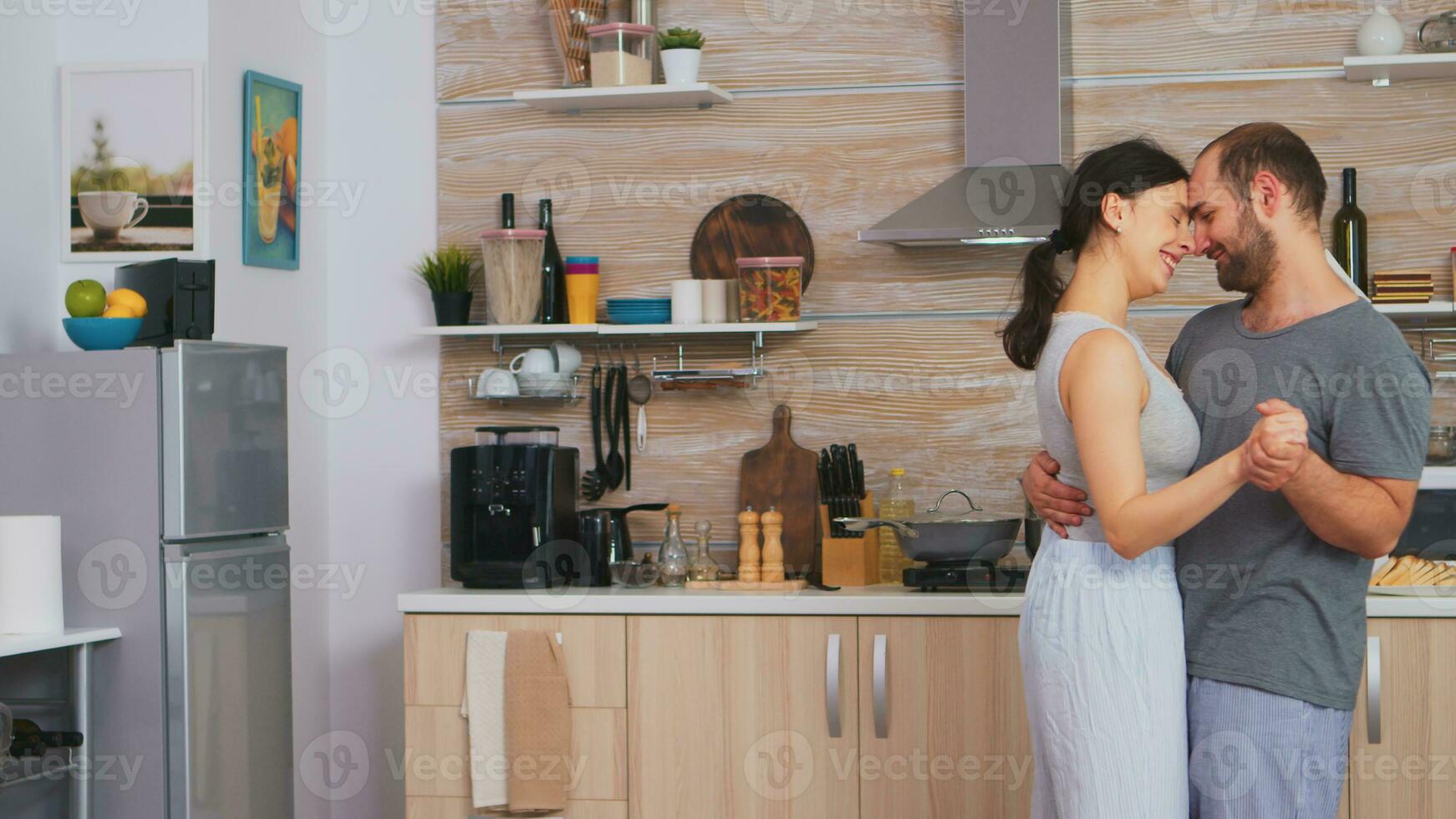authentisch Paar schleppend Tanzen während Frühstück im Küche tragen Pyjama. romantisch Moment im zwei, tanzen und Hingabe, intim glücklich spielerisch Morgen zum jung Mann und Gattin, Umarmen jeder andere foto