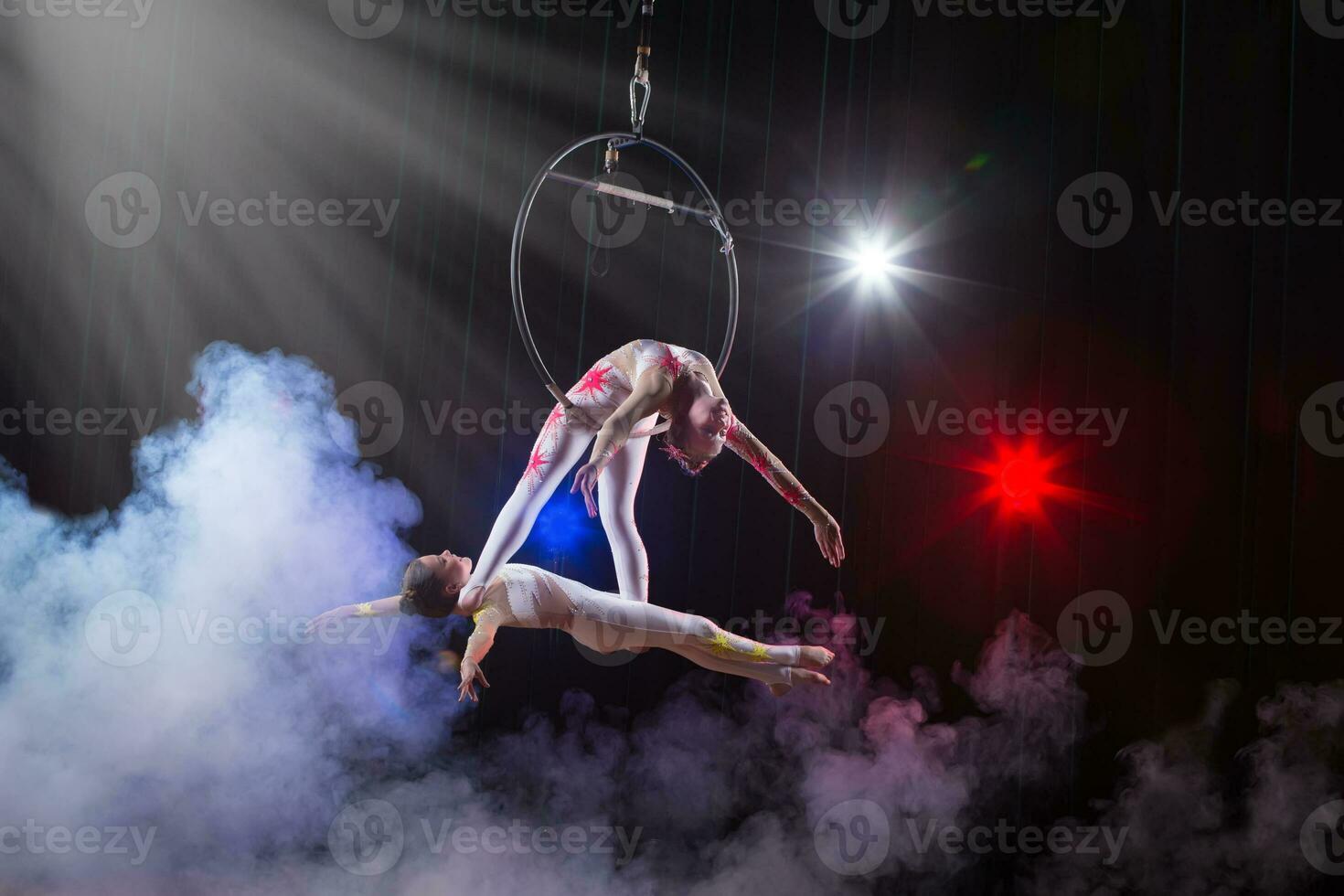 Zirkus Darstellerin Akrobat Leistung. zwei Mädchen ausführen akrobatisch Elemente im das Luft Ring. foto