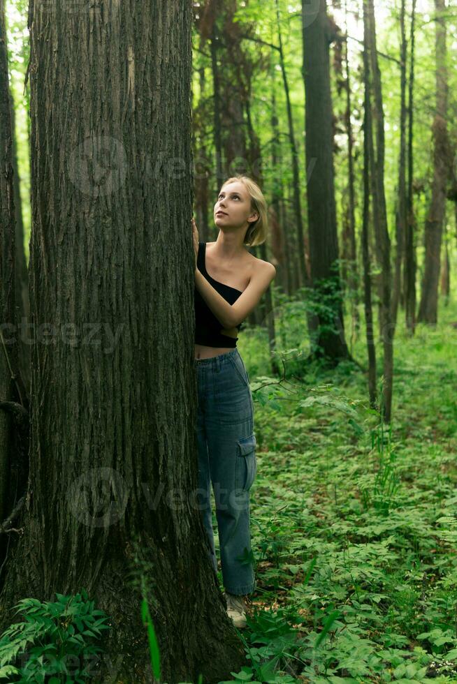 Mädchen Teenager im ein laubabwerfend Hain kommuniziert mit Bäume foto