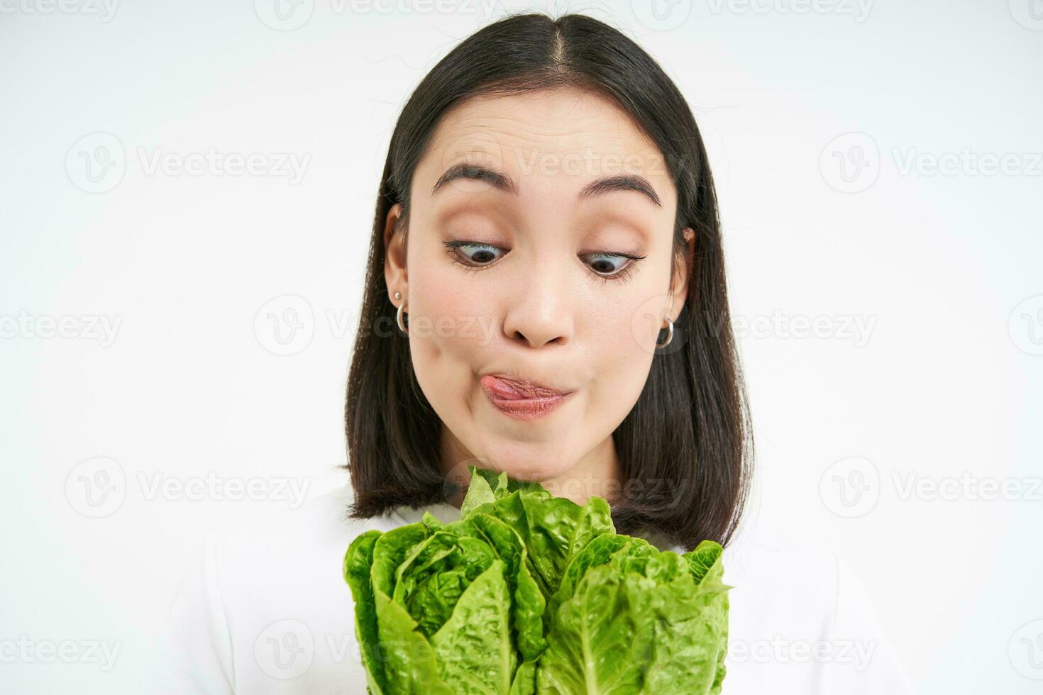 gesund Essen und vegan Lebensstil. schließen oben Porträt von lächelnd asiatisch Frau, sieht aus Glücklich, zeigt an ihr Gesicht mit Kopfsalat, isst Kohl, Weiß Hintergrund foto