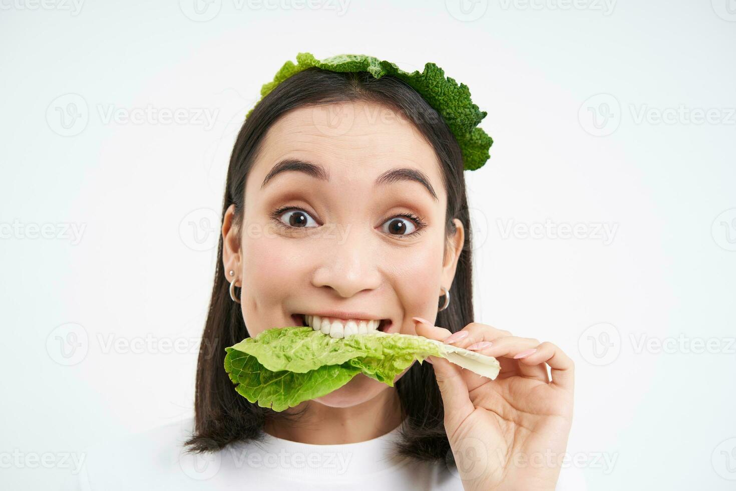 Glücklich, süß asiatisch Frau Essen Grün Kopfsalat, Vegetarier Likes oranisch Gemüse, Weiß Studio Hintergrund foto