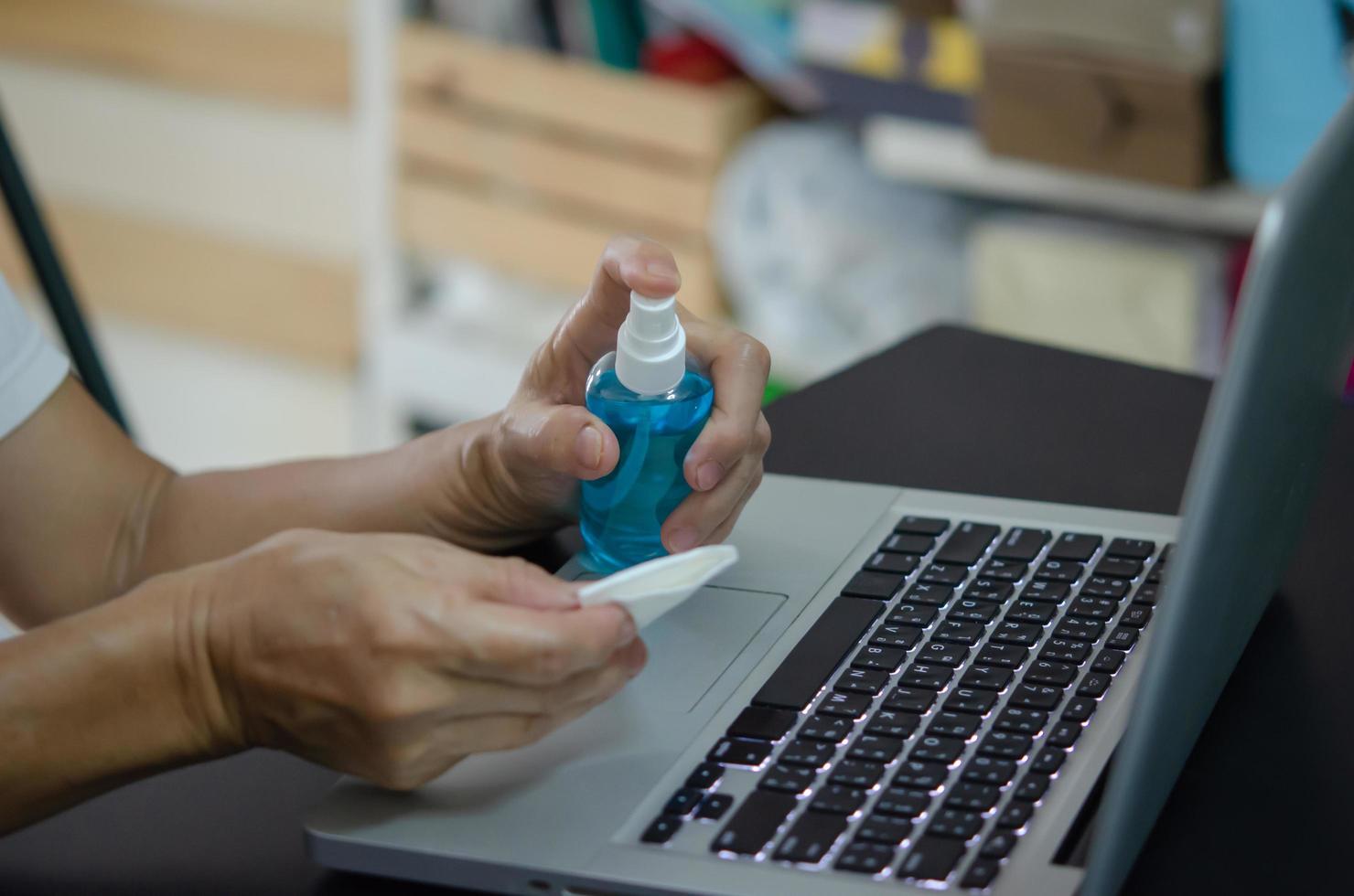 Sprühen von Alkohol, um den Computer zu reinigen und die Keime abzuwischen. Gesundheitskonzept. foto