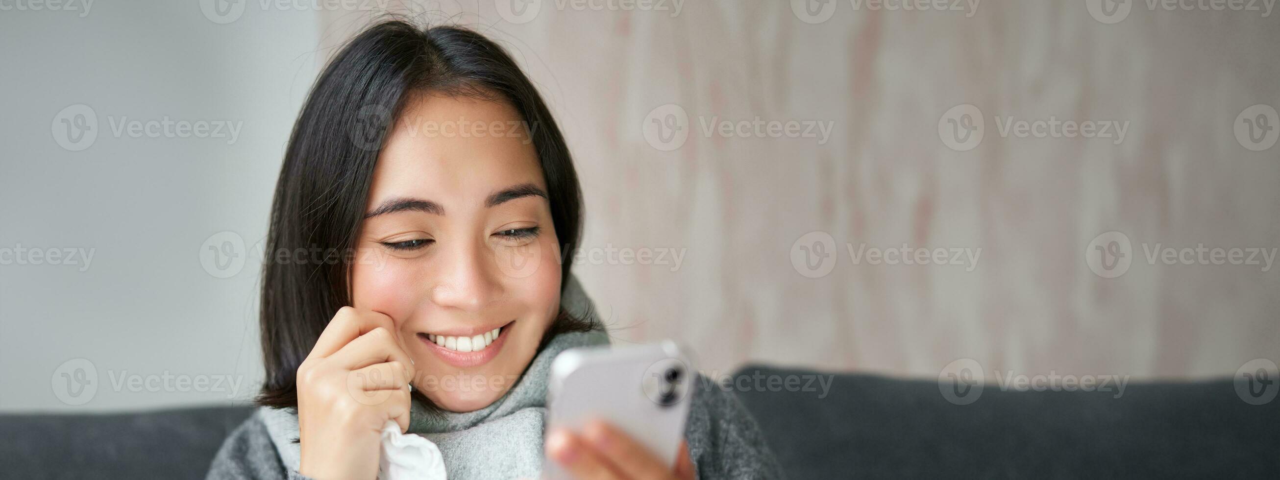 Porträt von Koreanisch Frau fühlt sich krank, halten Smartphone, Berufung Arzt gp zu erhalten Rezept, gefangen kalt, bleiben beim heim, mit Handy, Mobiltelefon Telefon foto