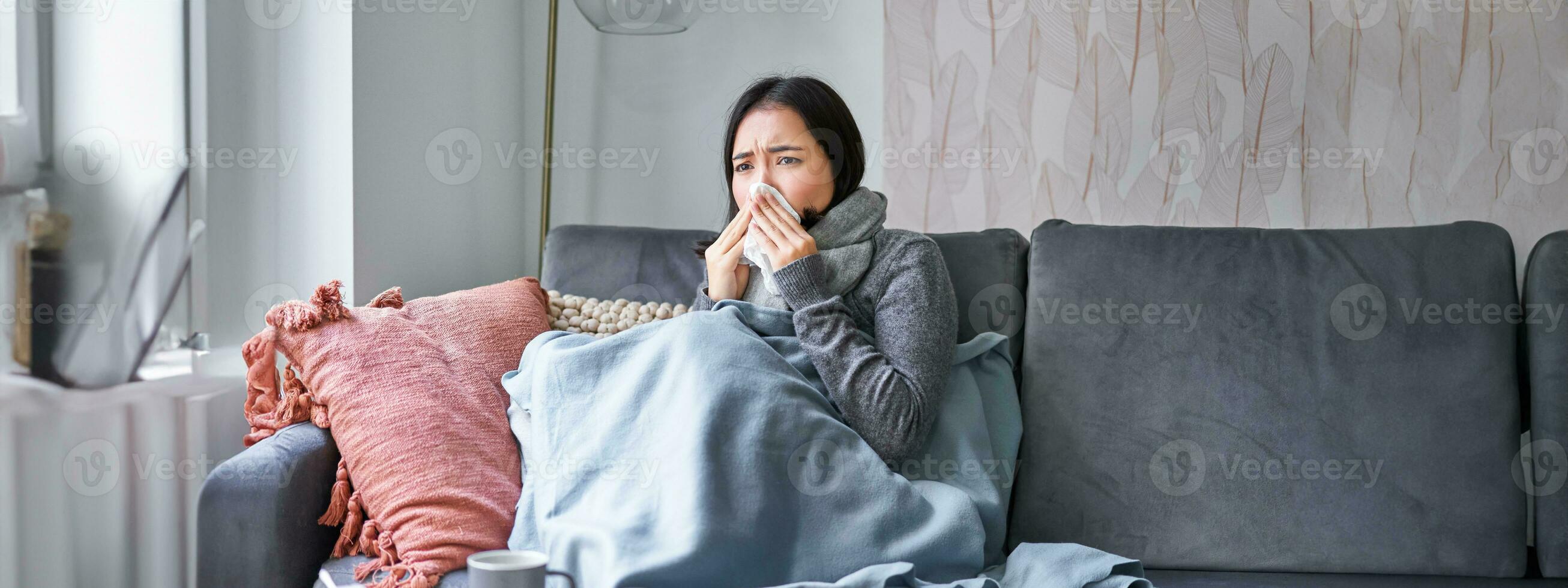 Koreanisch Frau fühlt sich nicht wohl, Niesen und Husten, fangen kalt, bleiben beim Zuhause mit Fieber und Temperatur, nehmen Medikation foto