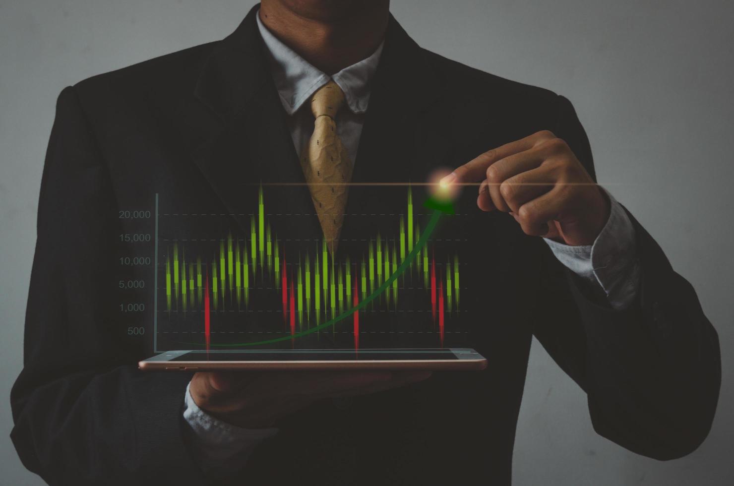 Geschäftsmann, der Tablette auf der Hand und den virtuellen Bildschirm des Symboldiagramms Börse hält. Investmentgeschäft und Konzeptfinanzierung foto