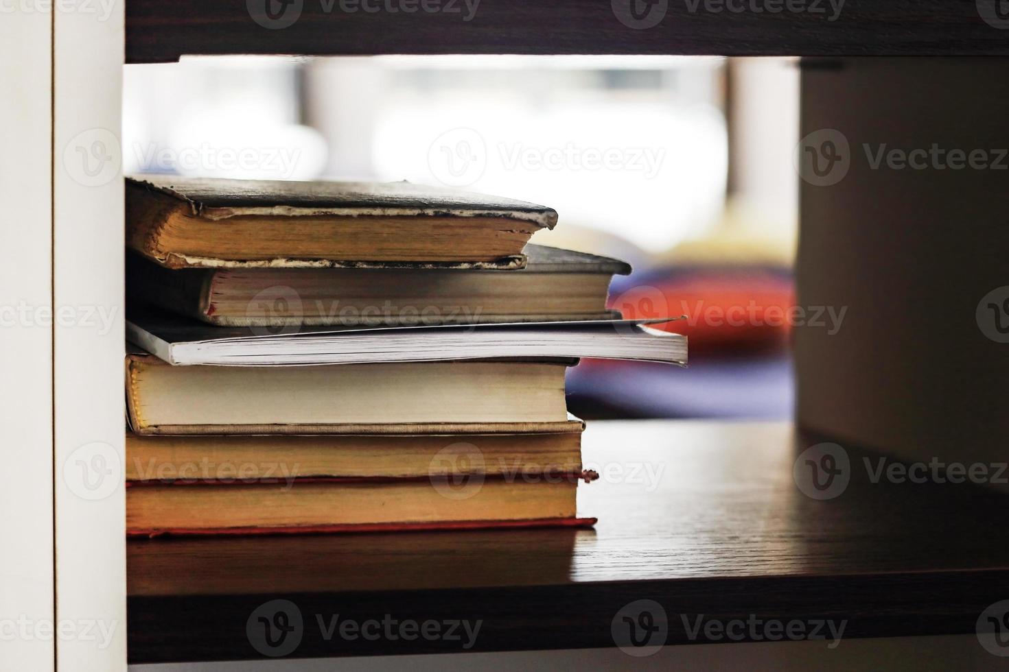 viele Bücher gestapelt auf schwarzem Regal mit Bokeh foto