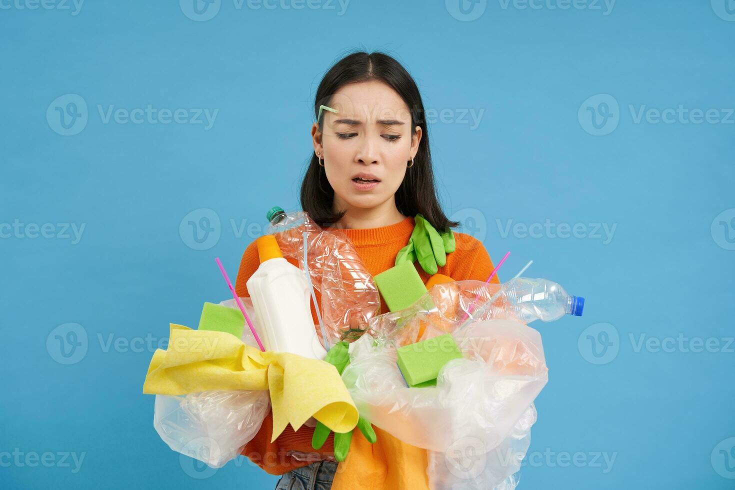 traurig asiatisch weiblich Student, hält Recycling Abfall, sammelt Plastik Müll zu nehmen es zu recyceln Center, Blau Hintergrund foto