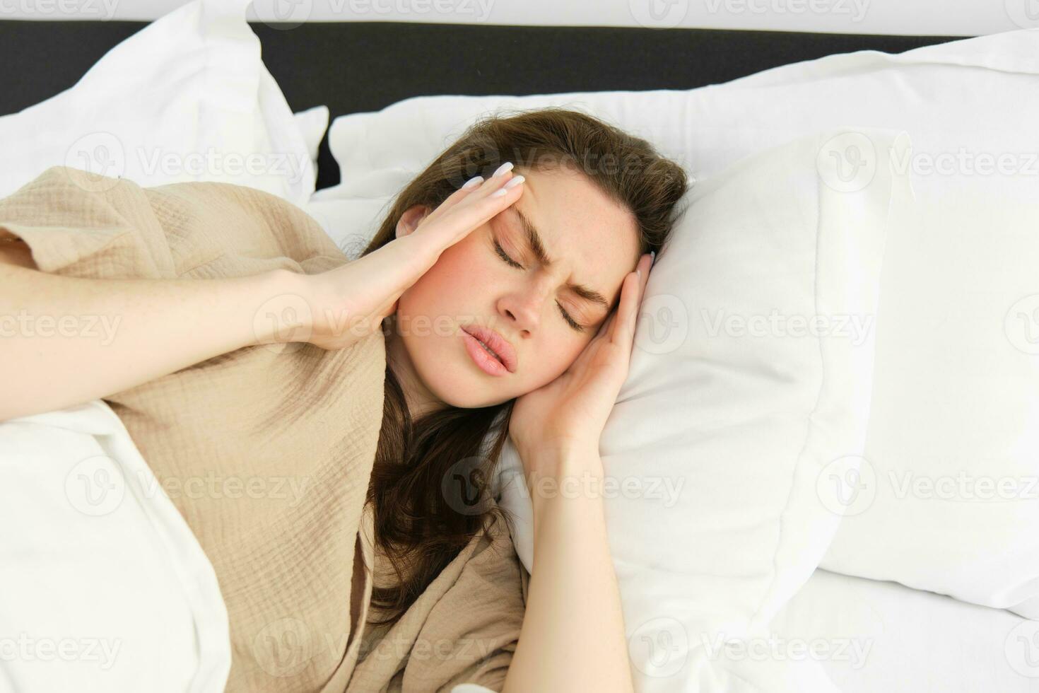 Frau Lügen im Bett und Gefühl nicht wohl, haben Kopfschmerzen, berühren ihr Kopf mit frustriert Gesicht, hat hoch Fieber oder Migräne. Konzept von Gesundheit und Menschen foto
