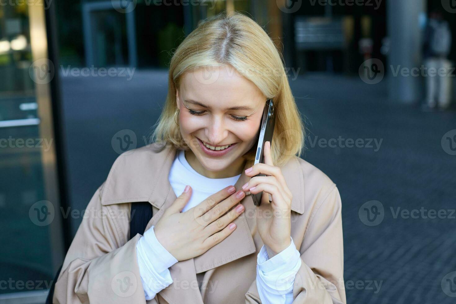 schließen oben Porträt von lächelnd, Lachen jung Frau, reden auf Handy, Mobiltelefon Telefon, Stehen draußen, Gehen auf Straße mit Smartphone und chatten foto