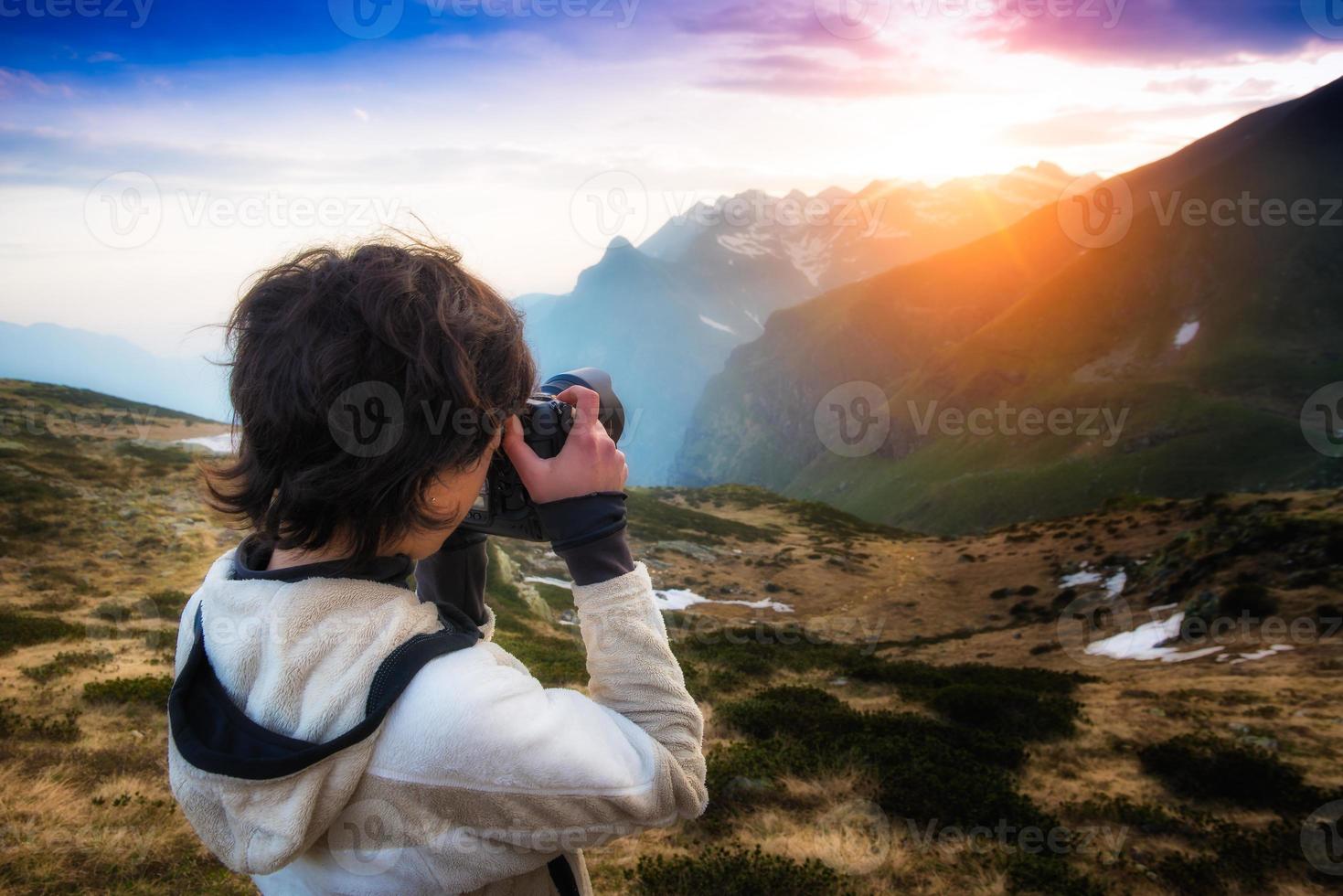 Mädchen fotografiert den Sonnenuntergang in den Bergen foto