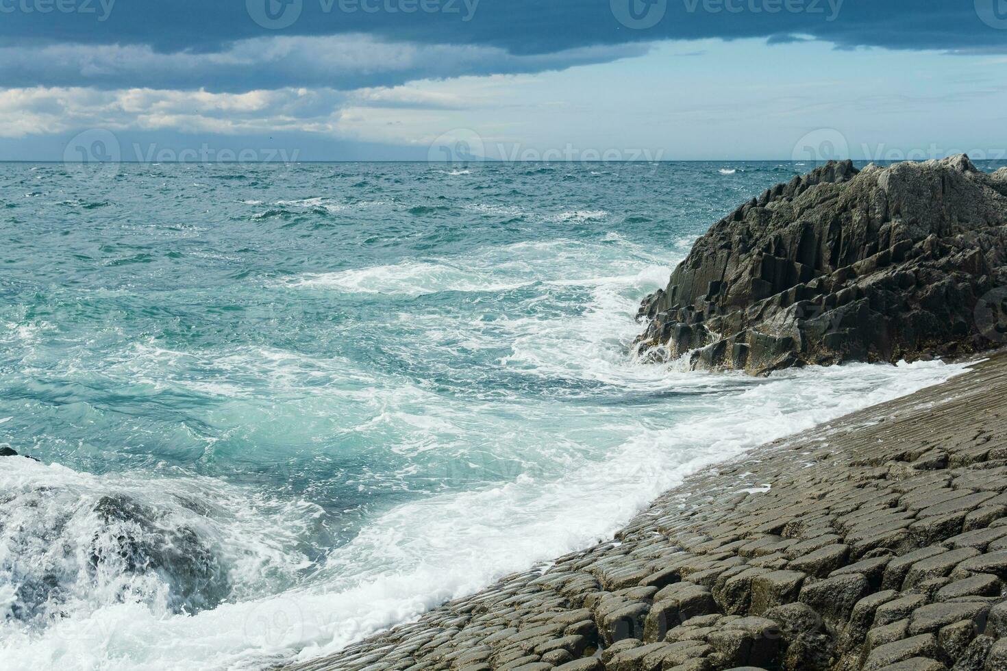 felsig Strand gebildet durch säulenförmig Basalt gegen das Surfen, Küsten Landschaft von das Kuril Inseln foto