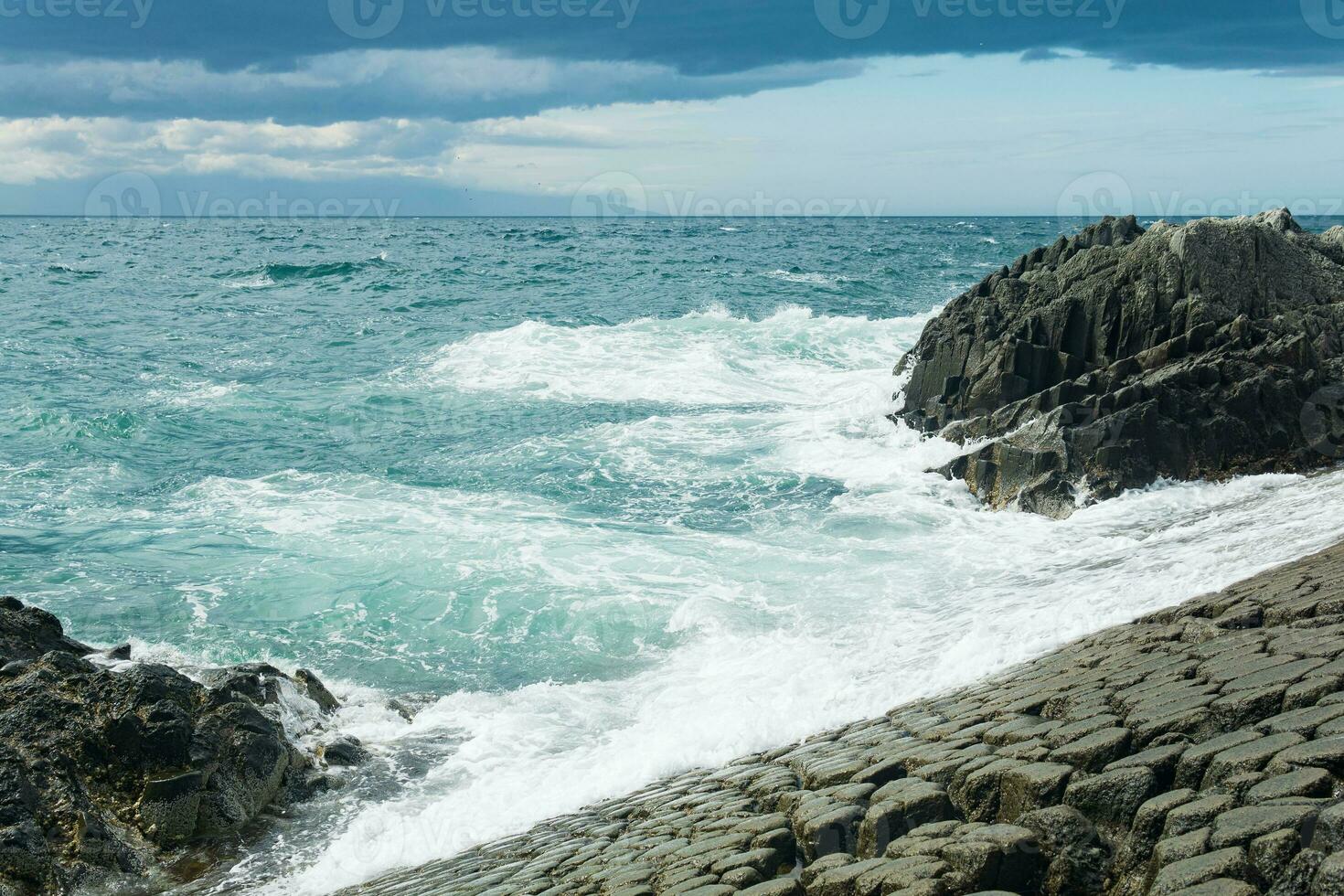 felsig Strand gebildet durch säulenförmig Basalt gegen das Surfen, Küsten Landschaft von das Kuril Inseln foto