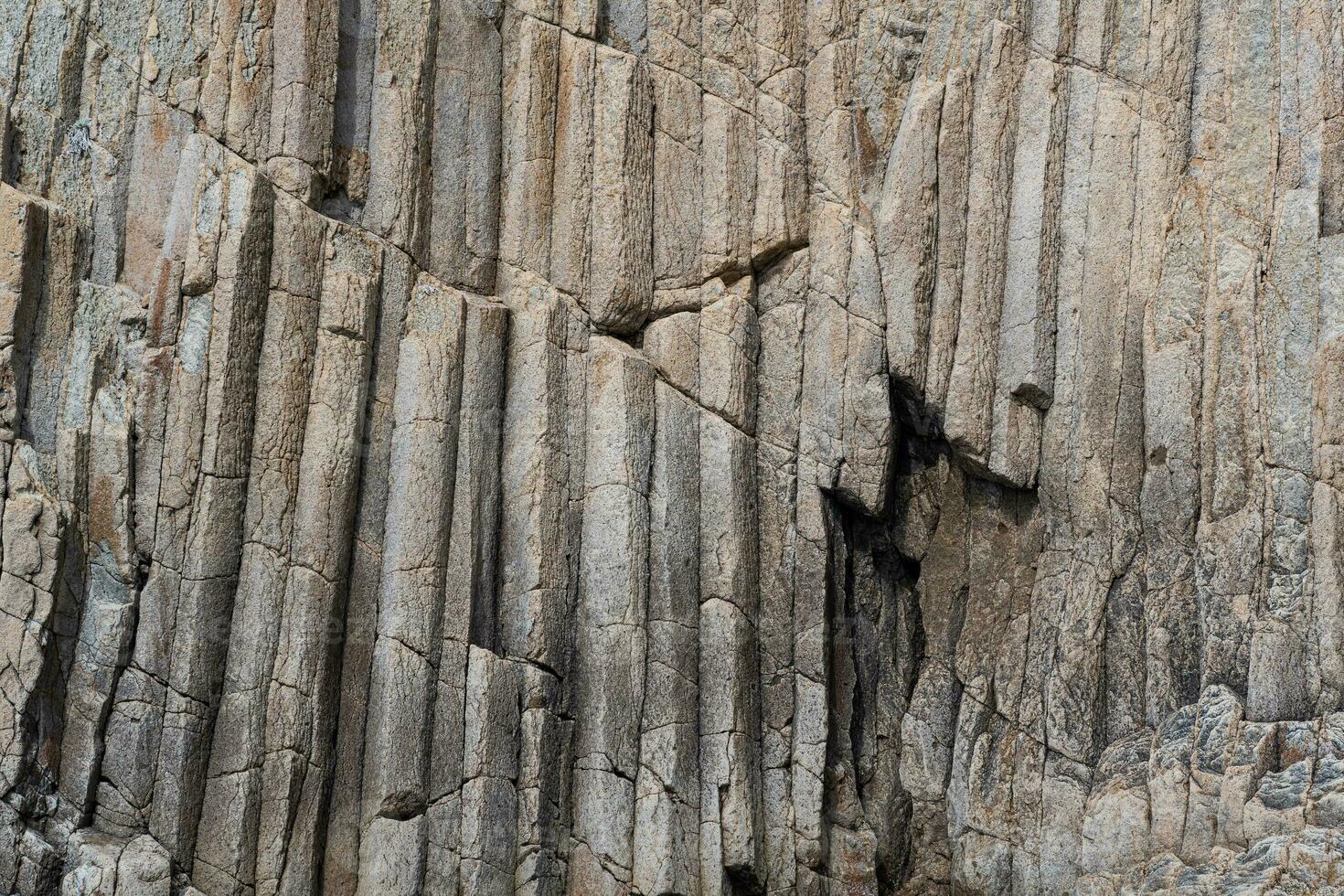 Oberfläche von ein Felsen Mauer gebildet durch säulenförmig Basalt foto