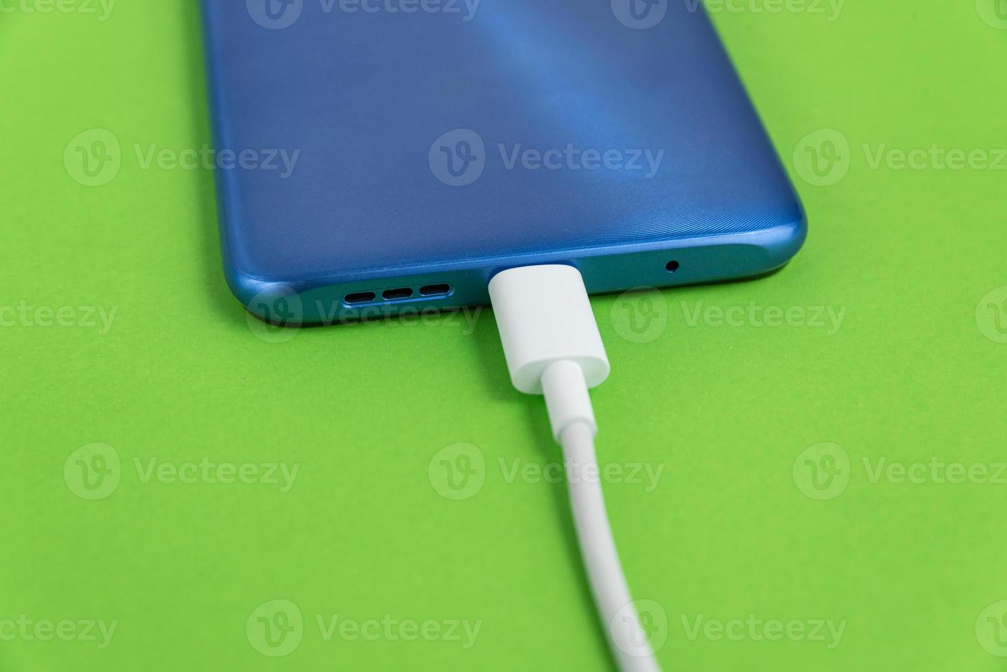 blaues Handy mit USB-Kabeltyp verbunden - Aufladen foto