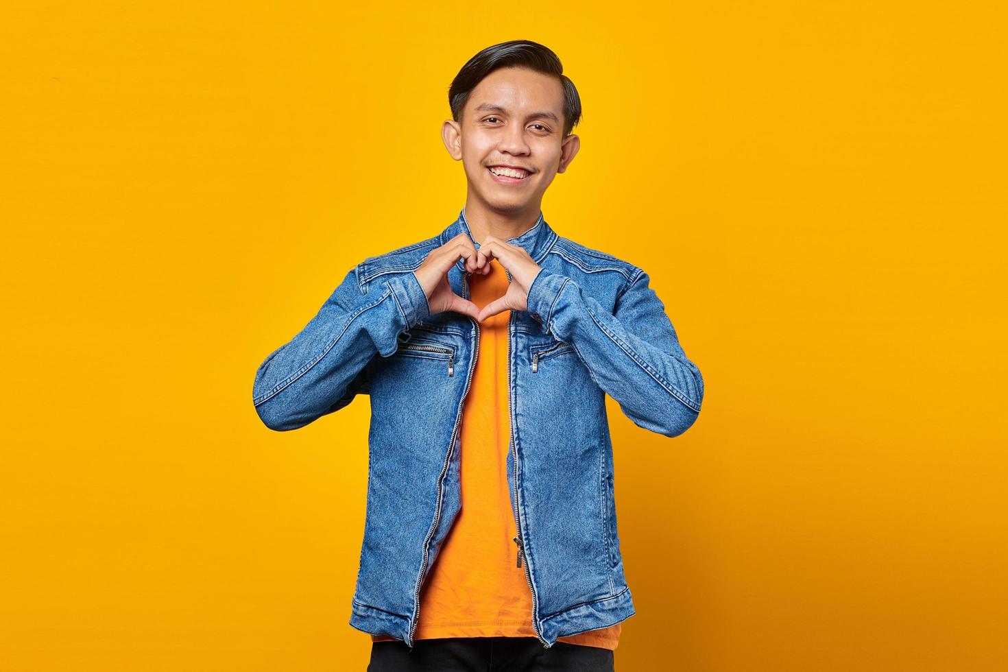 Porträt eines fröhlichen jungen asiatischen Mannes, der Herzzeichen mit den Fingern macht foto