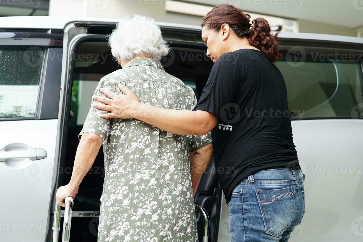 pflegekraft hilft asiatischen älteren frauen mit behinderungspatienten, in ihr auto zu steigen, medizinisches konzept. foto