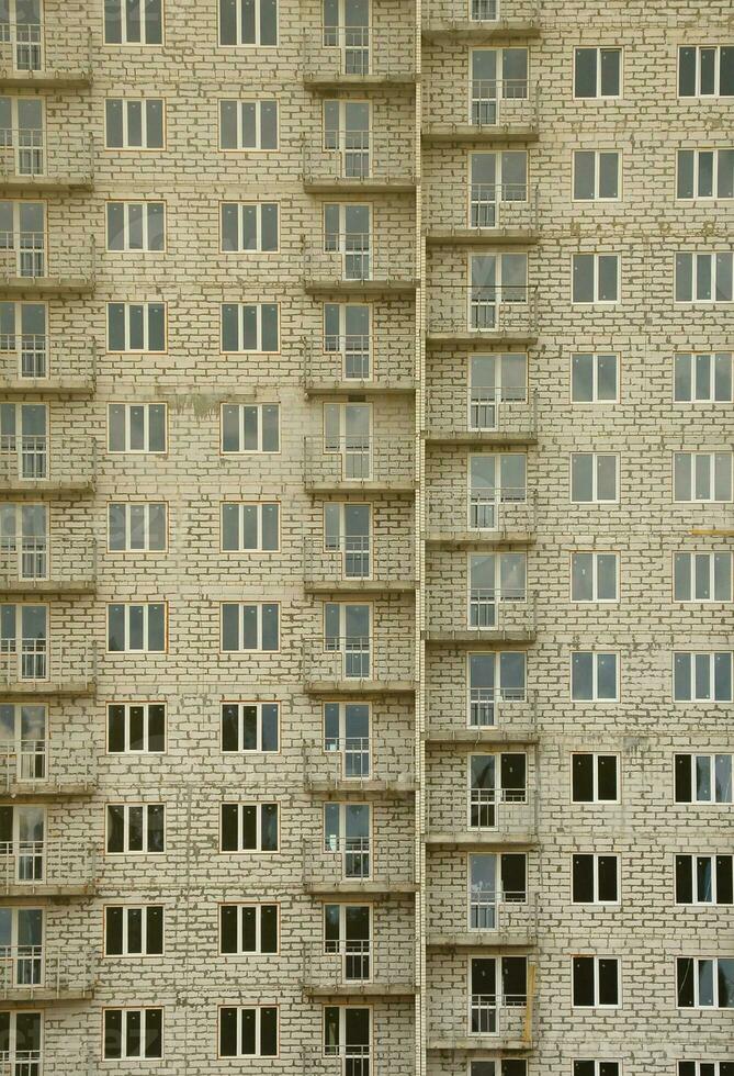 Strukturmuster einer russischen Whitestone-Wohnhauswand mit vielen Fenstern und Balkon im Bau foto