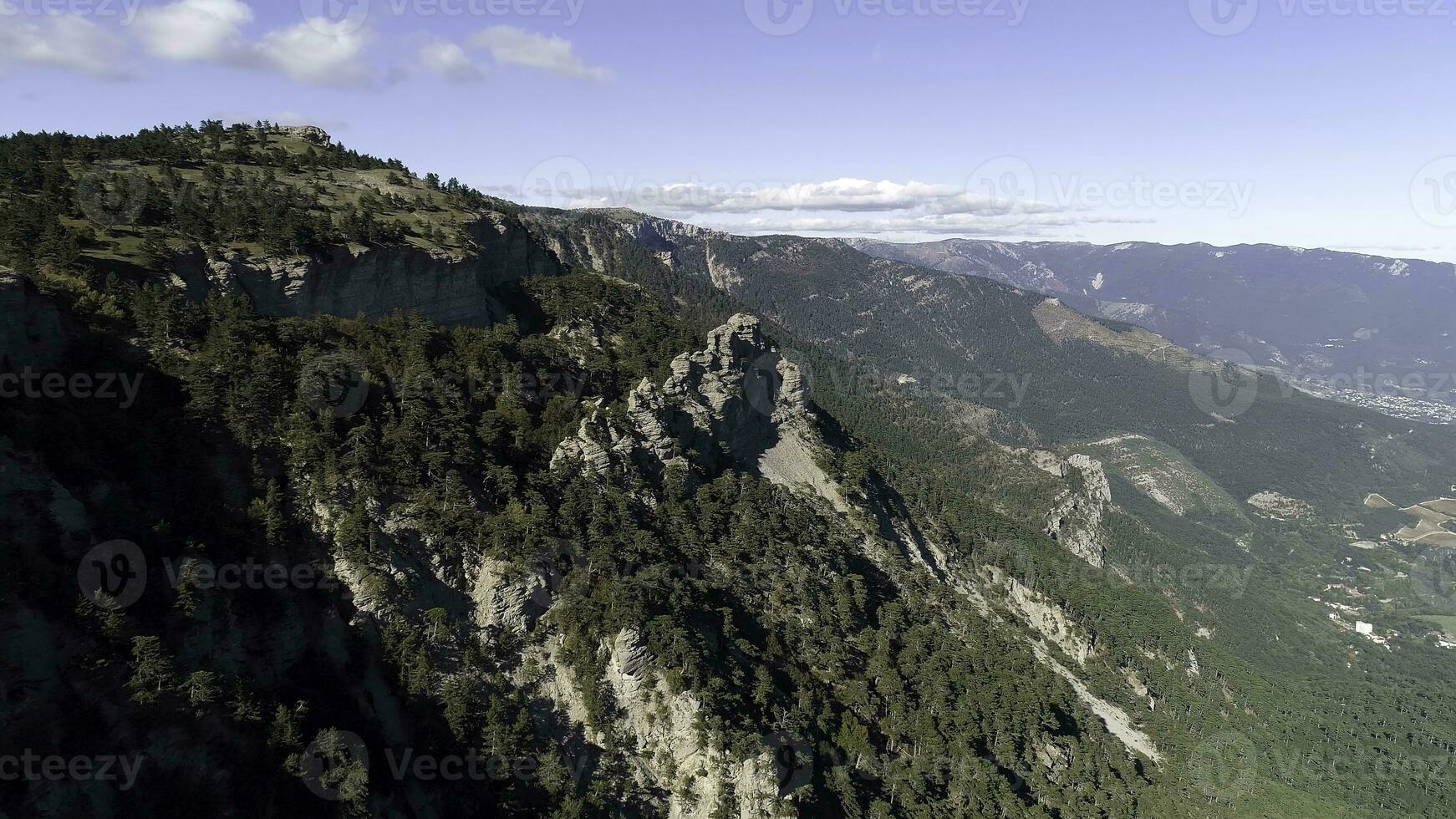 das Berge und Klippen bedeckt durch Grün Wald. Schuss. Kiefer Bäume auf das Berg Pisten mit ein Riese Felsen unter das hell Sonne Licht. foto