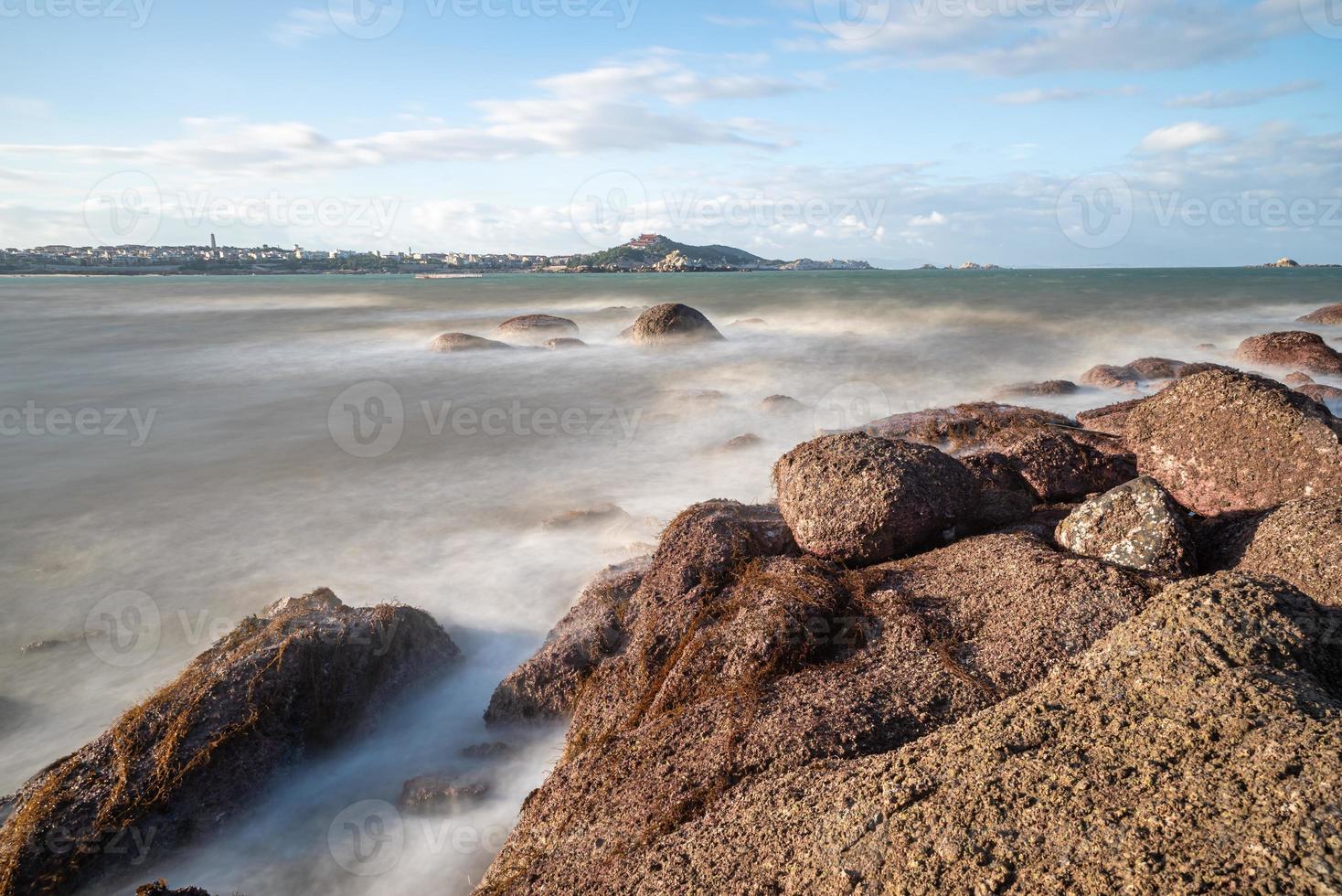 morgens scheint die sonne auf die felsen und wellen am strand foto