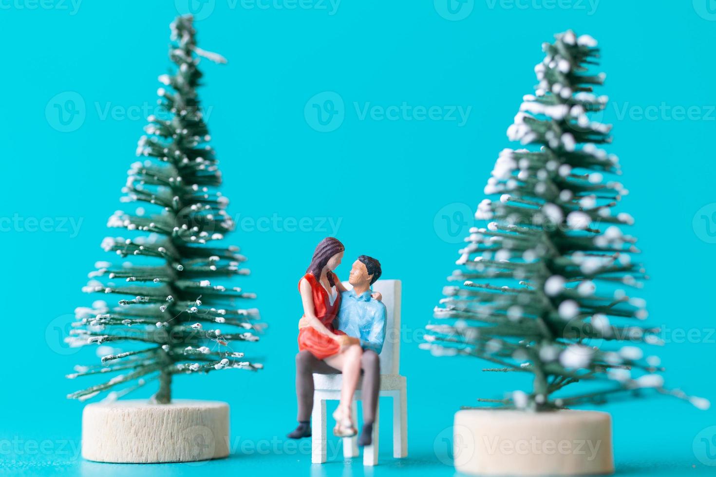Miniaturmenschen, verliebtes Paar sitzt neben einem Weihnachtsbaum foto