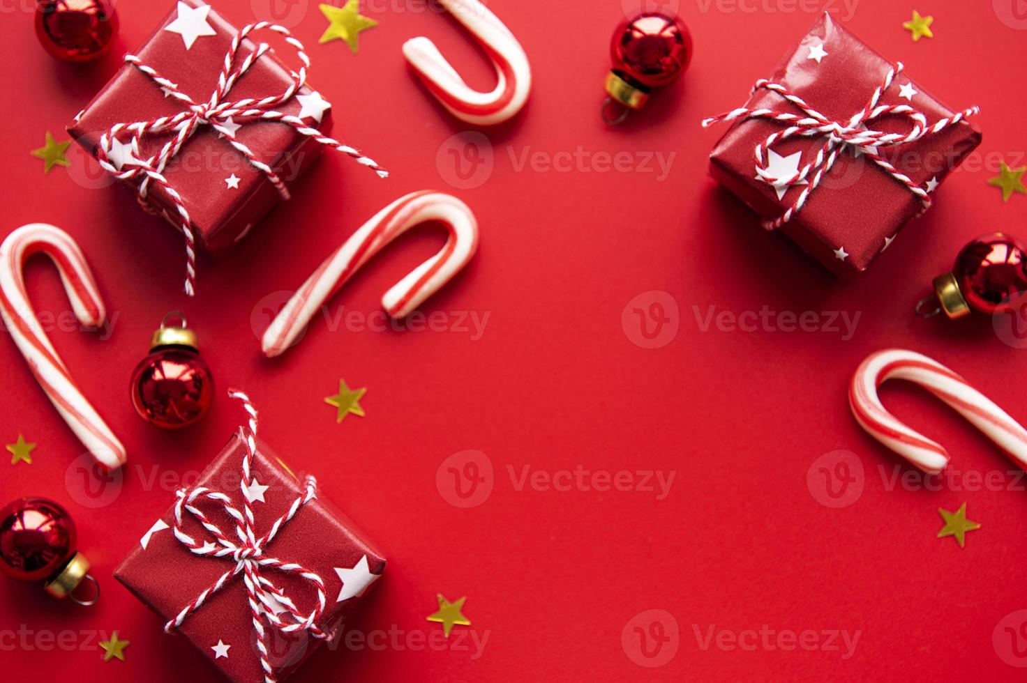 rote Weihnachtskugeln, Geschenkboxen und Zuckerstangendekoration auf rotem Hintergrund mit Kopierraum foto