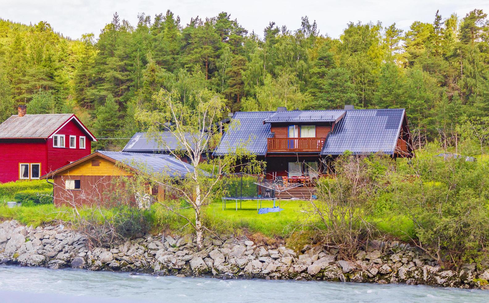 Türkisfarbenes Schmelzwasser fließt in einem Fluss durch ein Dorf in Norwegen foto