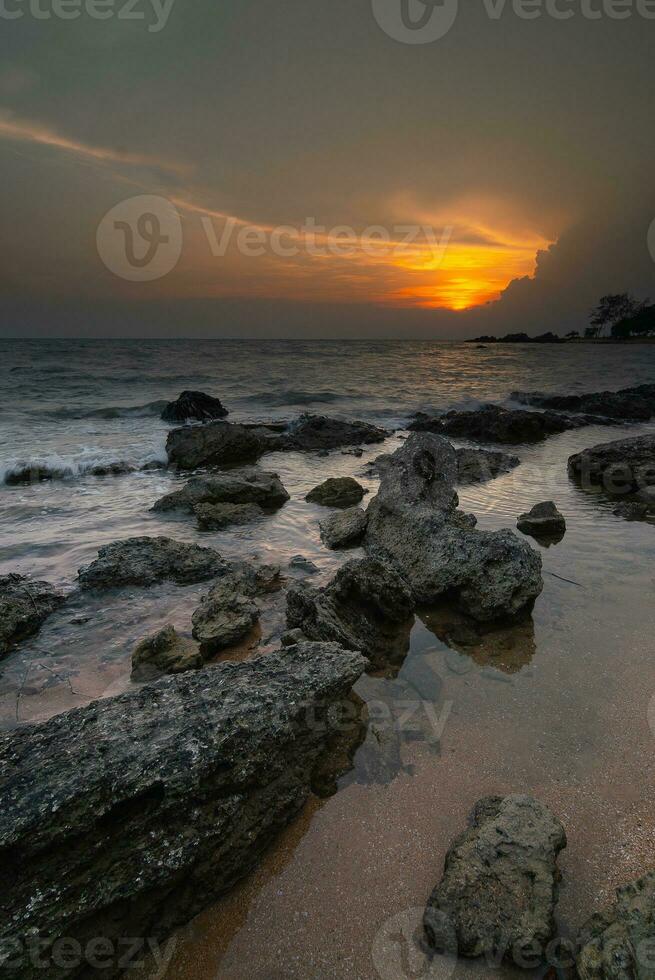 Sonnenuntergang beim das Strand mit Felsen und Wasser foto