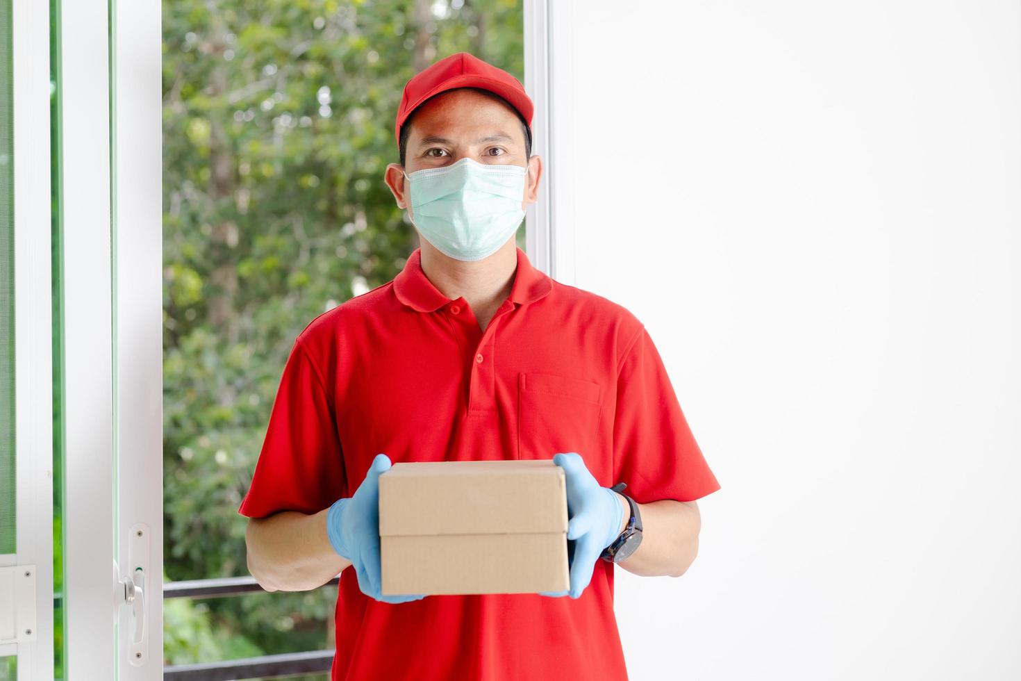 ein lieferant in einem roten kleid hält einen paketkasten. foto