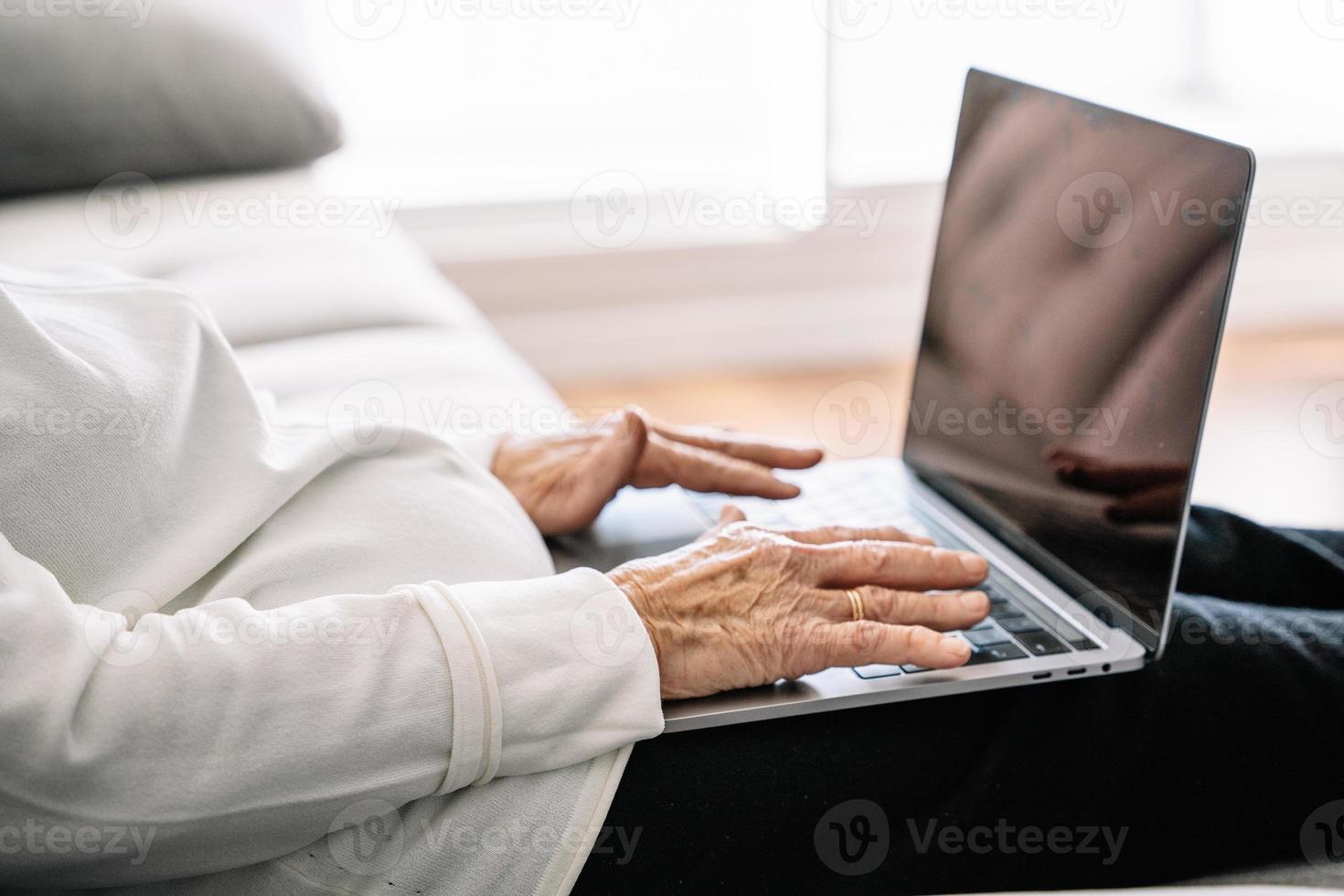 Ruhige ältere Frau, die Laptop im Wohnzimmer durchsucht foto