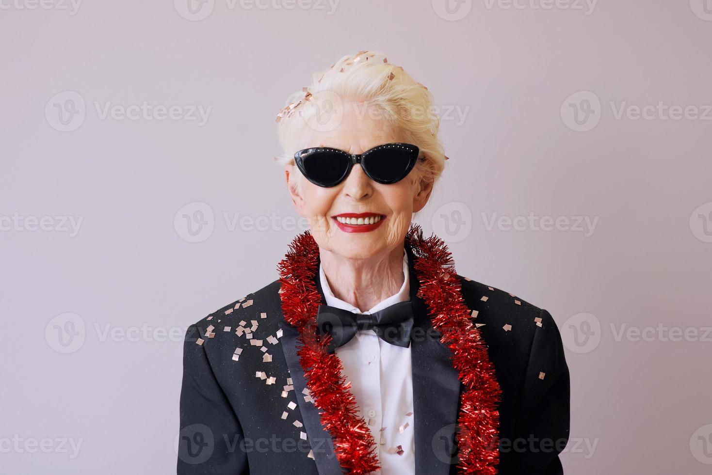 Schöne, stilvolle, reife ältere Frau in Sonnenbrille und Smoking, die das neue Jahr feiert. Spaß, Party, Stil, Feierkonzept foto