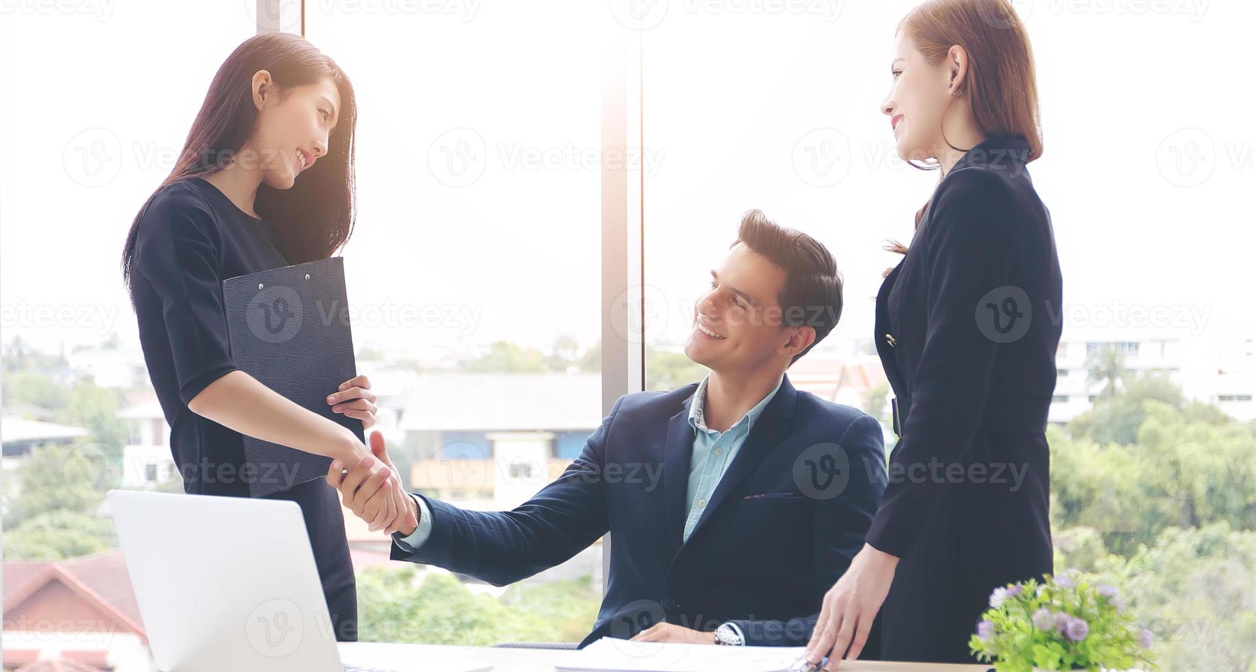 Geschäftsleute, die sich die Hände schütteln und ihre Zustimmung zur Vertragsunterzeichnung und zum Abschluss eines Meetings lächeln foto