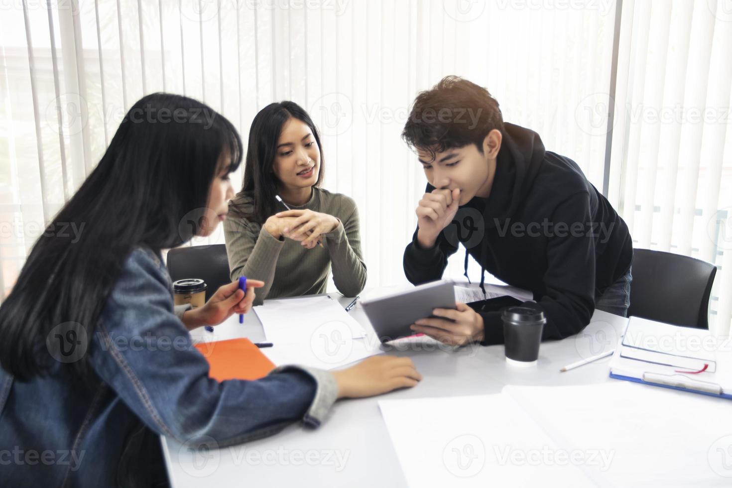 Gruppenschüler lächeln und haben Spaß und die Verwendung des Tablets hilft auch, Ideen in der Arbeit und im Projekt zu teilen. und rezensiere das Buch auch vor der Prüfung foto