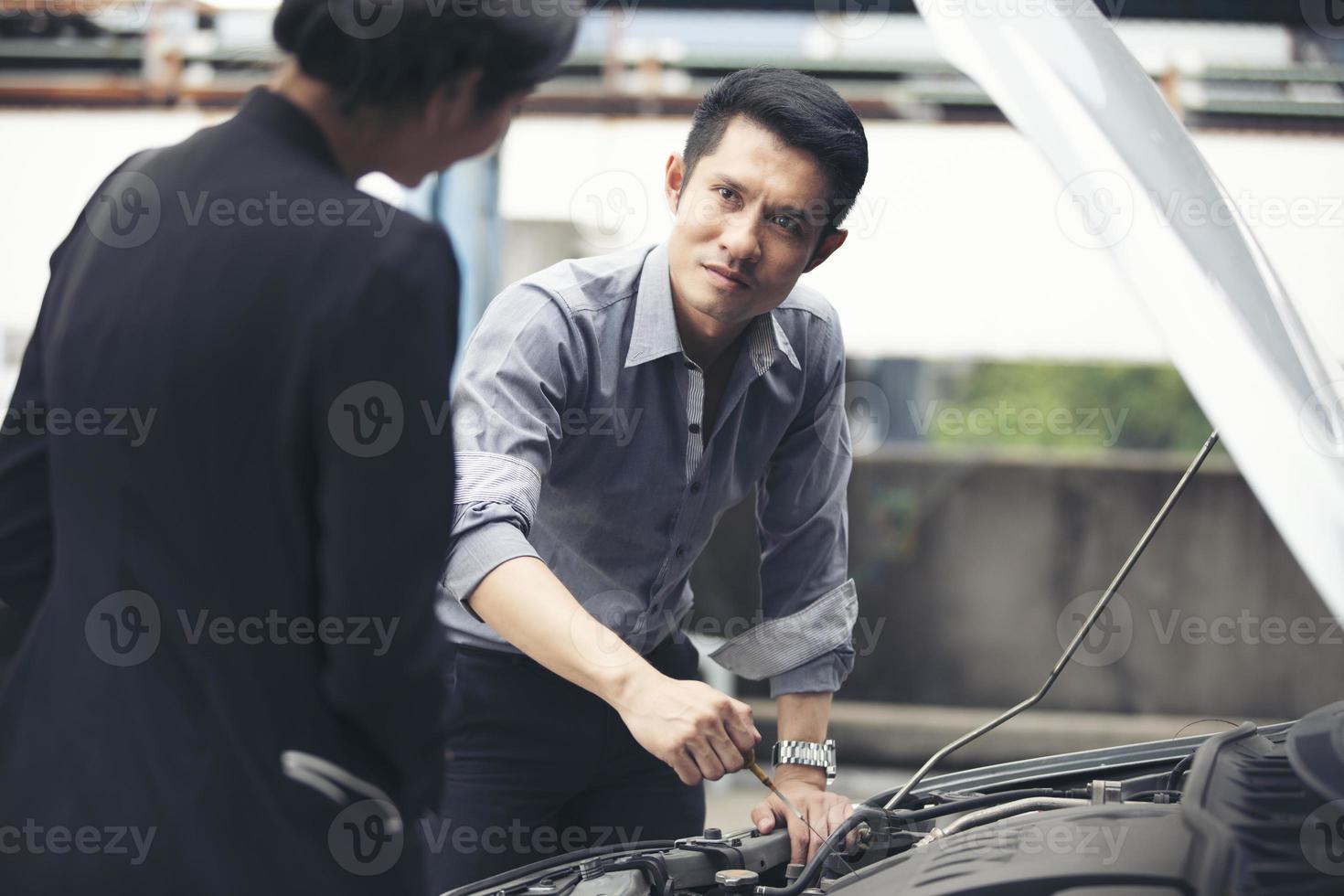 Geschäftsleute helfen Geschäftsfrauen, kaputte Autos zu überprüfen und zu reparieren foto