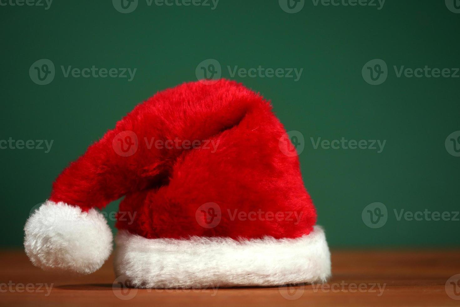 rote Weihnachtsmütze mit Kopienraum auf grünem und hölzernem Hintergrund foto