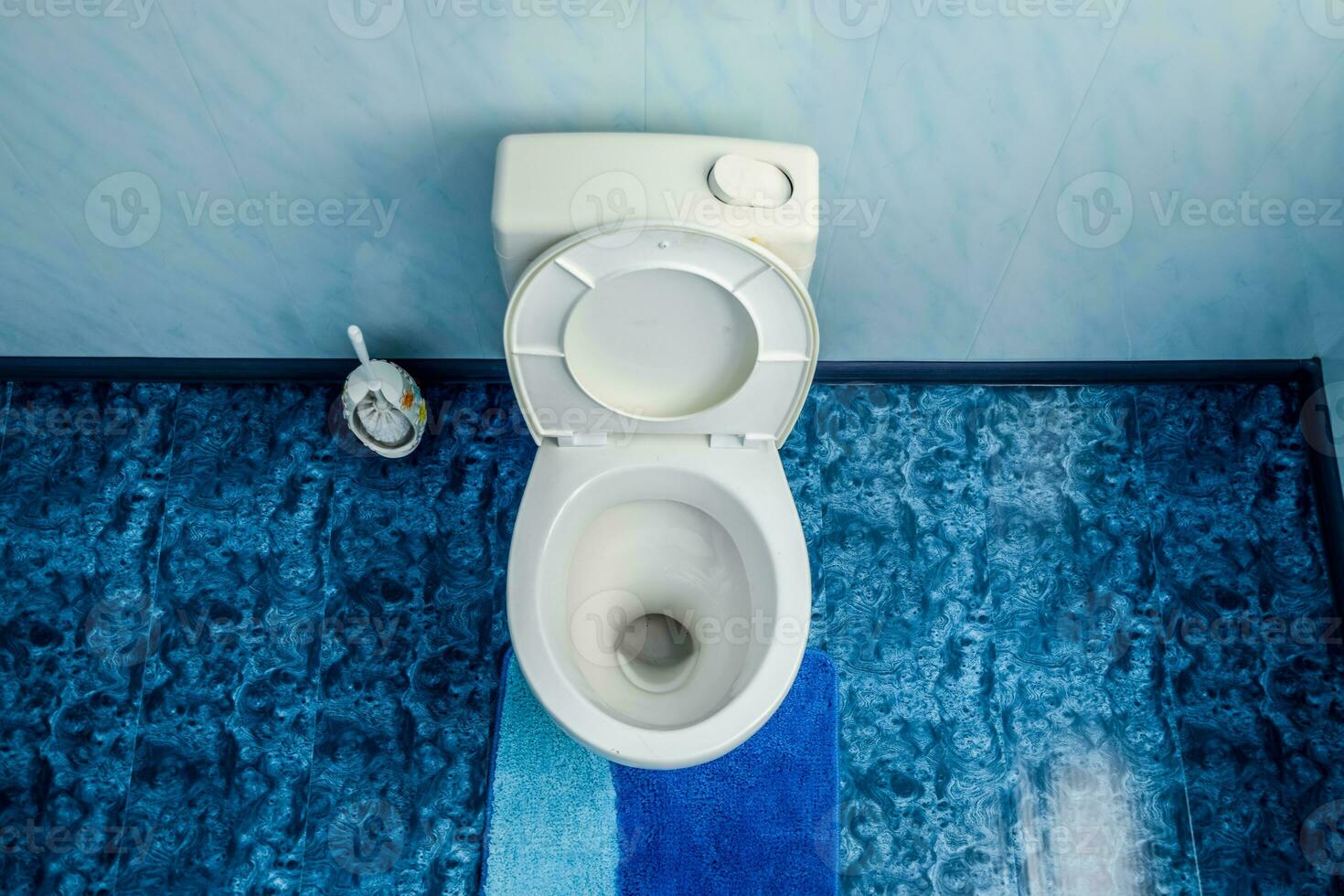 Toilette Schüssel im Toilette, Toilette Bürste auf das Seite. Blau Fußboden im das Toilette foto