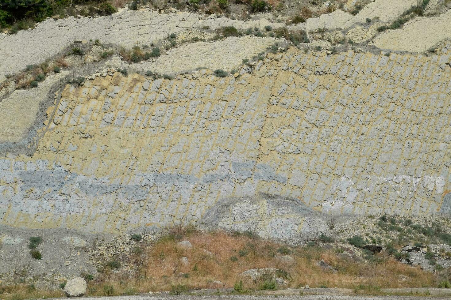 Steigung von das Berg mit Schichten von sedimentär Felsen. vertikal gelegen sedimentär Felsen auf zusammenbrechen Hang. foto