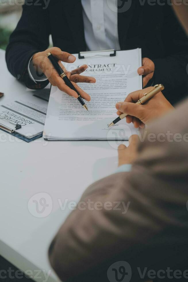 geschäftsleute und anwälte diskutieren vertragspapiere mit messingwaage auf dem schreibtisch im büro. gesetz, juristische dienstleistungen, beratung, justiz und gesetz konzeptbild mit filmkorneffekt foto