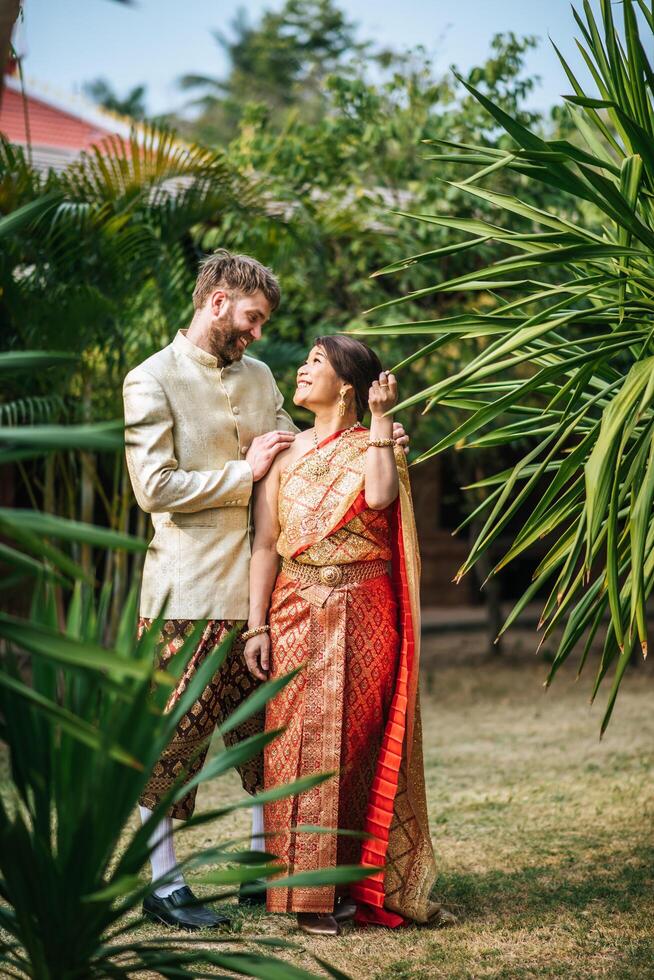 asiatische braut und kaukasischer bräutigam haben romantische zeit mit thailandkleid foto