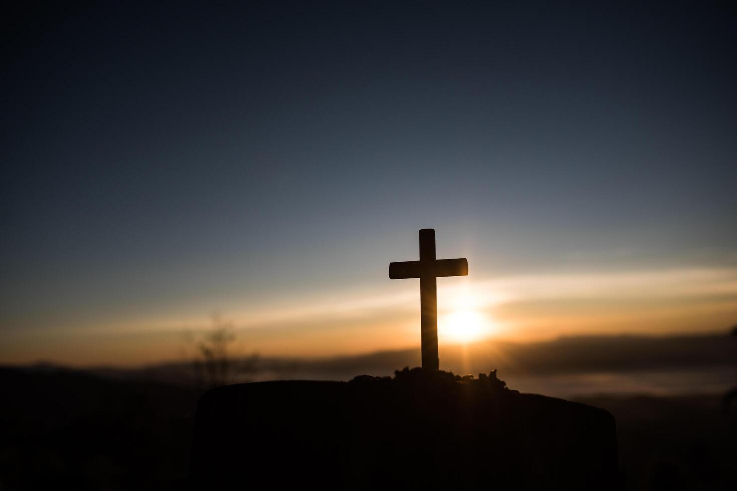 Silhouette des katholischen Kreuzes und des Sonnenaufgangs foto