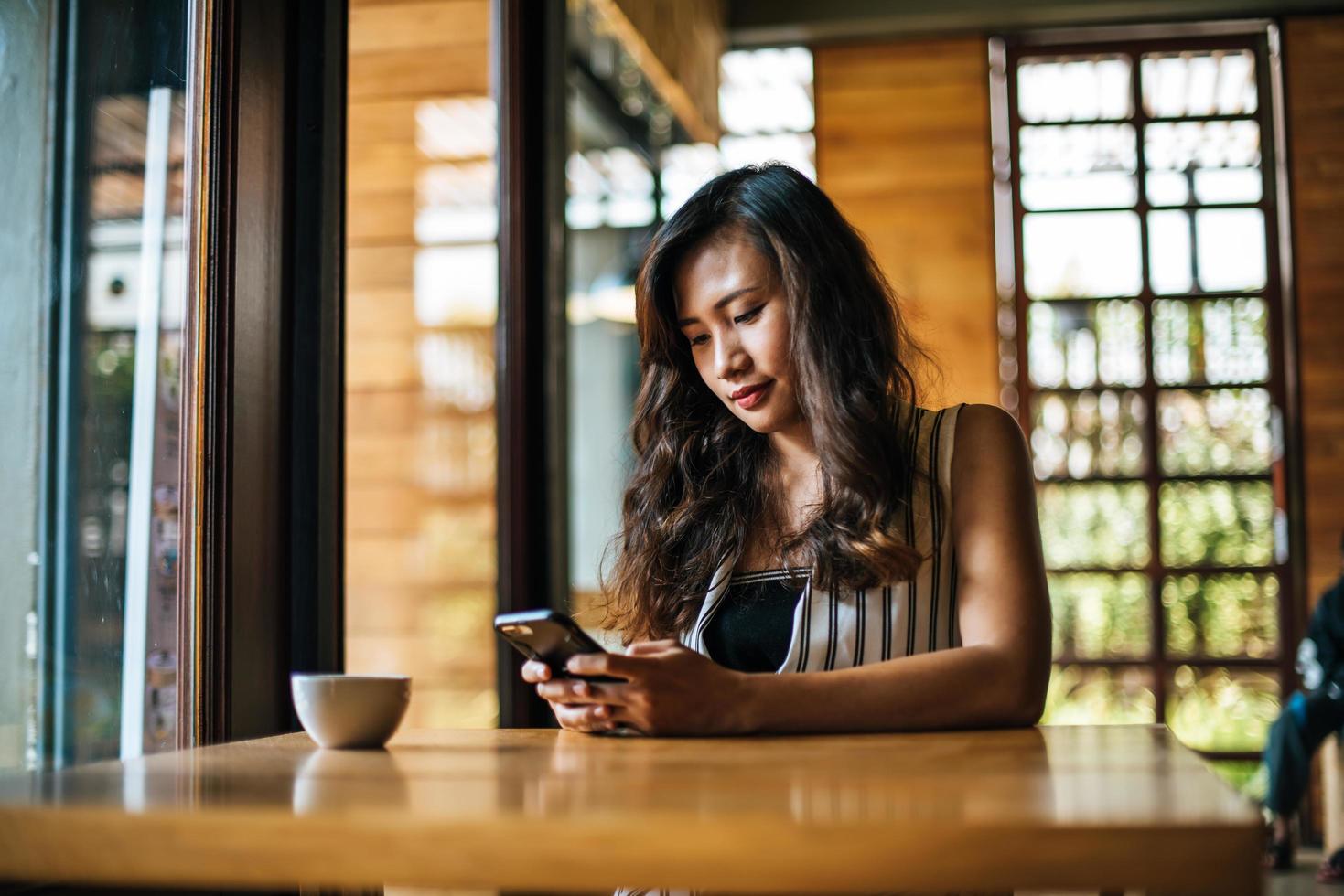 Frau sitzt und spielt ihr Smartphone im Café foto