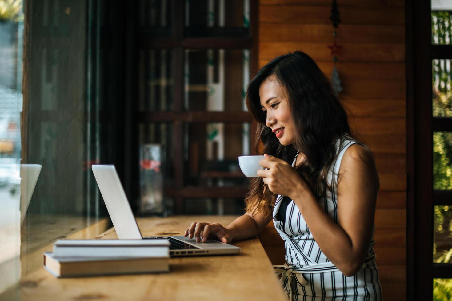 schöne Frau, die mit Laptop-Computer im Café-Café arbeitet foto