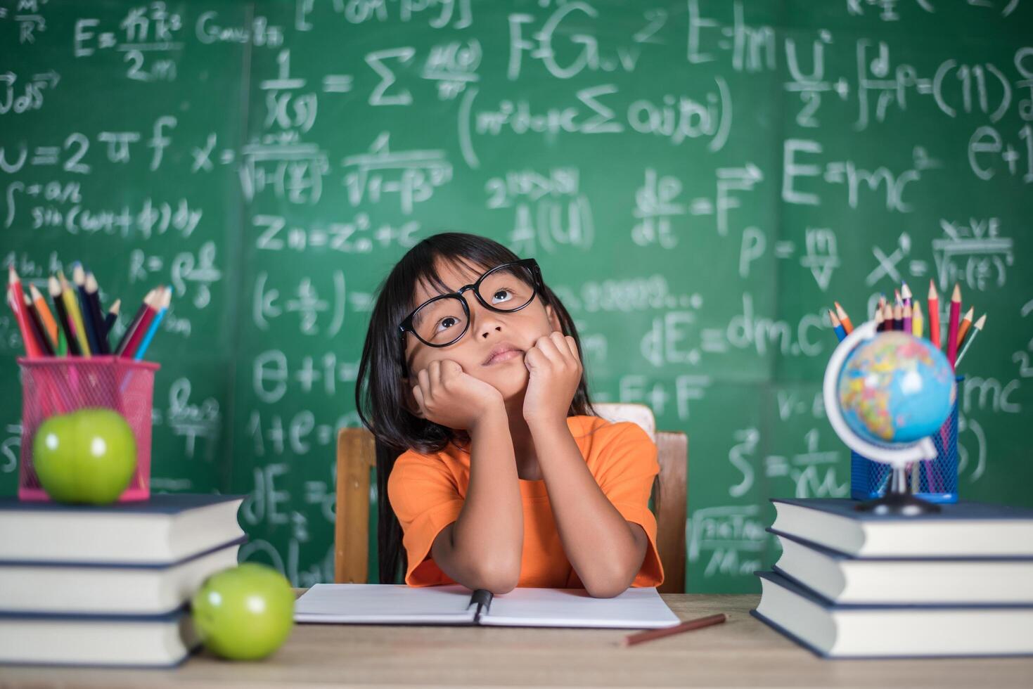 nachdenkliches kleines Mädchen mit Buch in der Nähe einer Schulbehörde foto