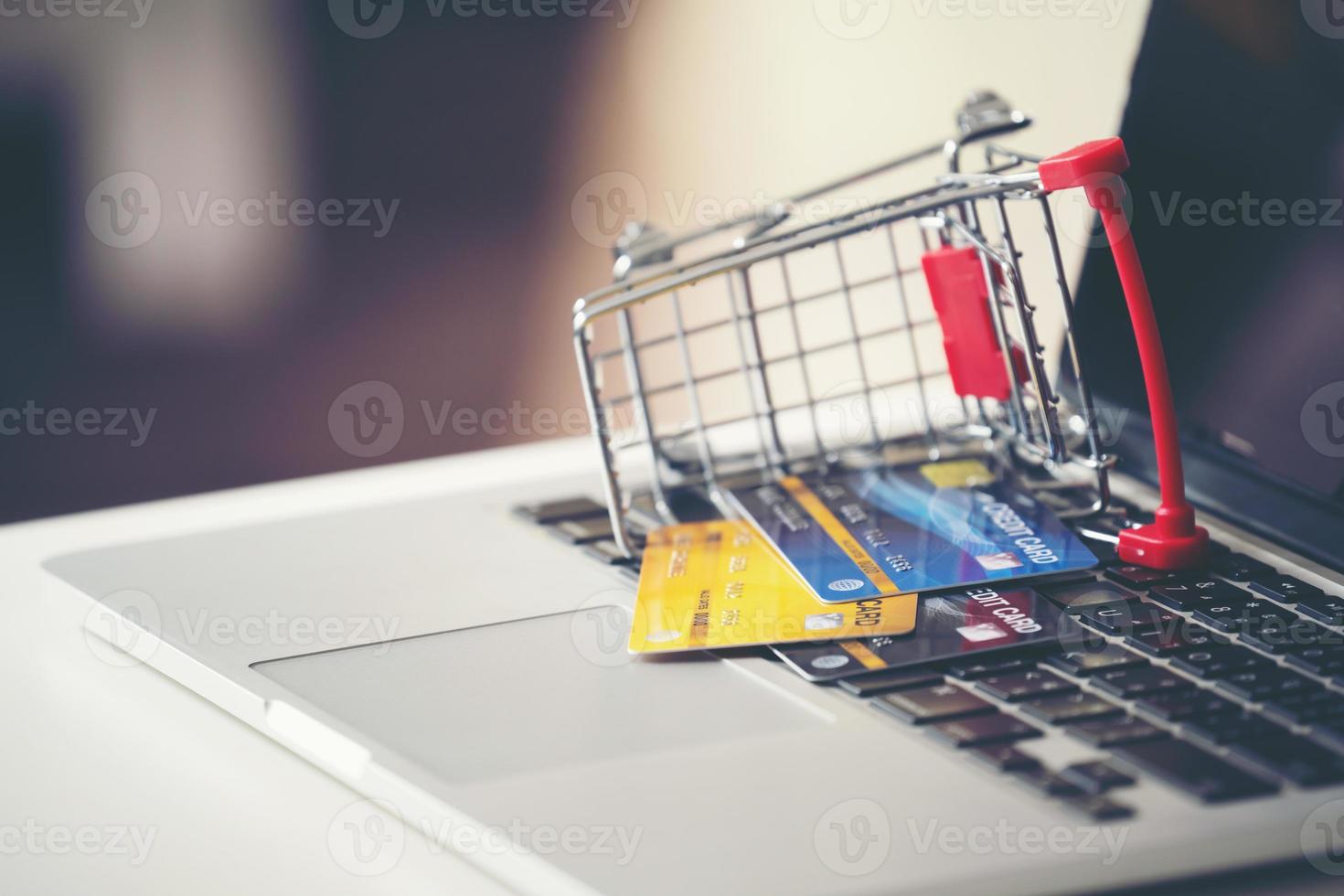 Einkaufswagen und Kreditkarte mit Laptop auf dem Schreibtisch foto