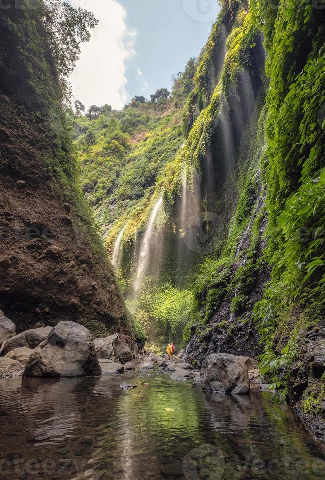 schöner Madakaripura-Wasserfall, der in felsiges Tal fließt foto
