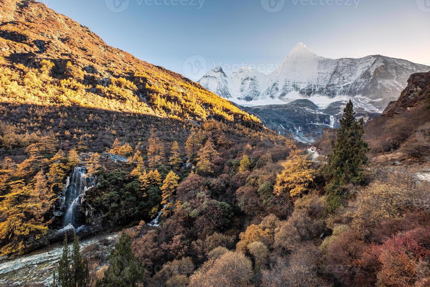 Mount Yangmaiyong mit Wasserfall im Herbstwald am Abend. Yading Naturschutzgebiet foto