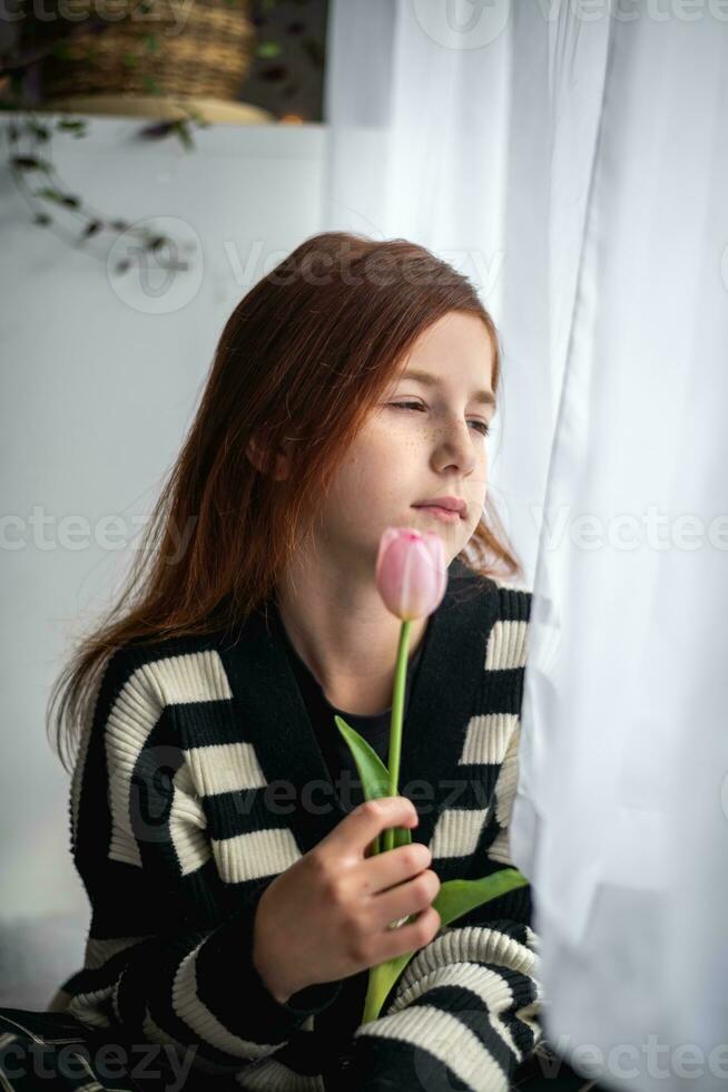 ein nachdenklich Teenager Mädchen sieht aus aus das Fenster. Nachdenklichkeit, Traurigkeit, Einsamkeit foto