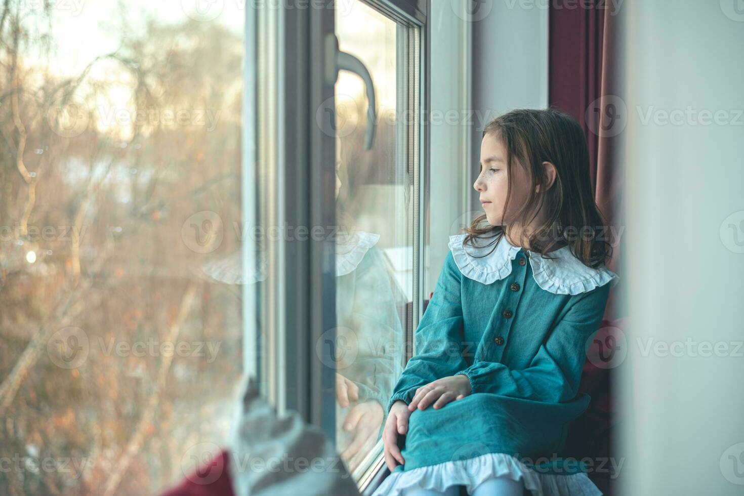 ein nachdenklich süß Mädchen sitzt und sieht aus aus das Fenster foto